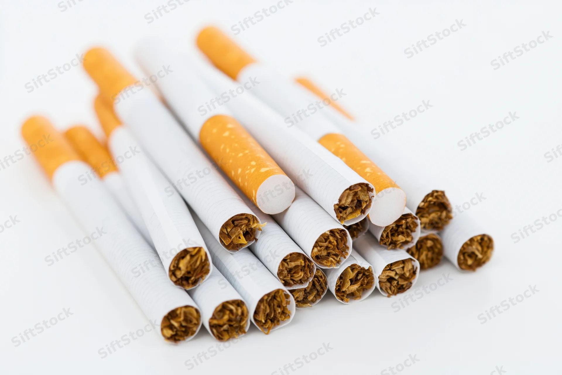 Unlit cigarettes scattered in a small heap on white background