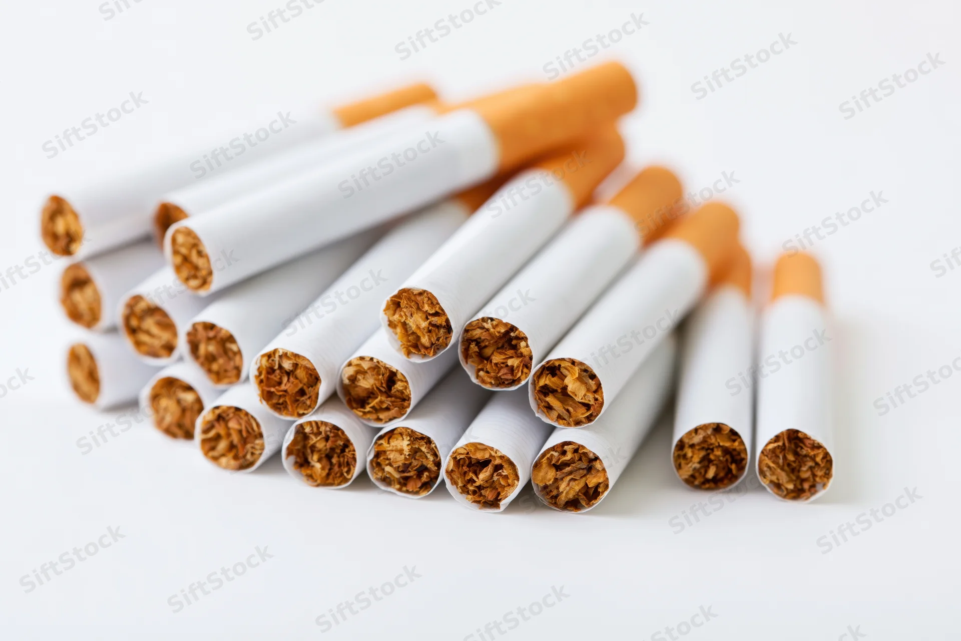 Unlit cigarettes piled together on a white surface