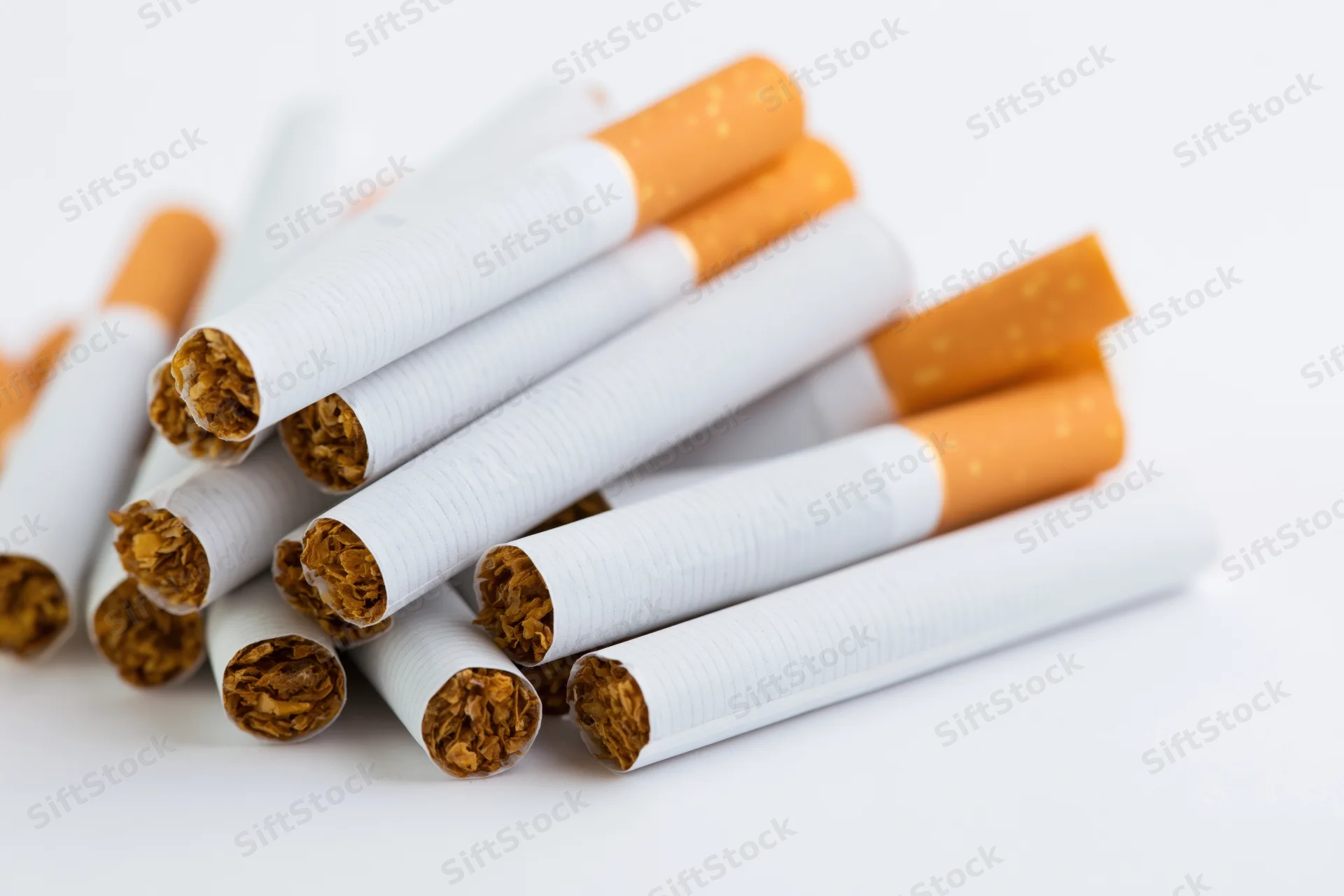 Unlit cigarettes piled together on a white surface