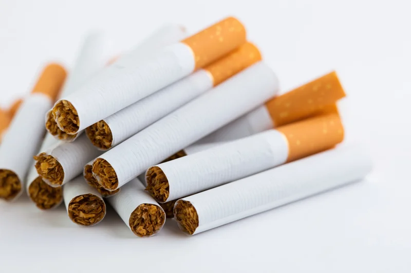 Unlit cigarettes piled together on a white surface
