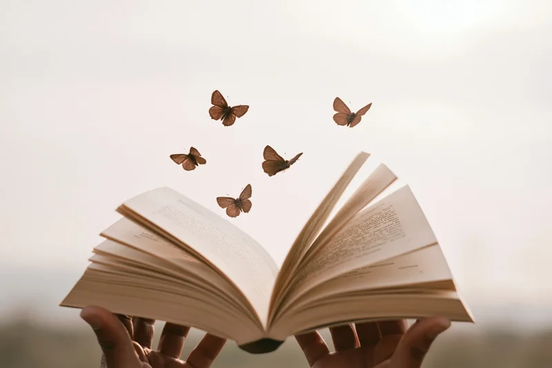 Hands holding open book with butterflies flying from pages