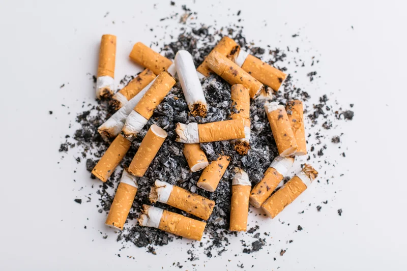 Cigarette butts and ash scattered on a white surface