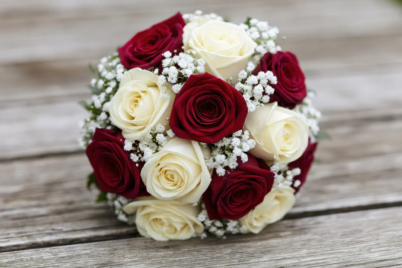 Round bridal bouquet of red and white roses on wooden surface