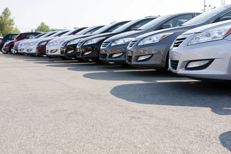 Row of sedans and hatchbacks parked diagonally on asphalt lot