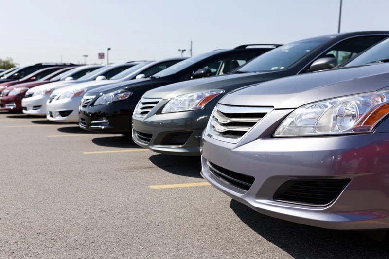 Row of sedans and hatchbacks parked diagonally in a dealership lot