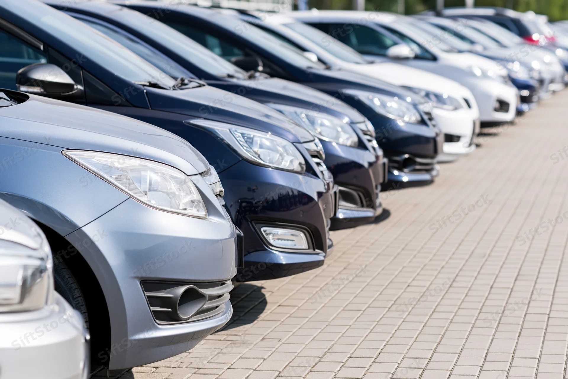 Row of sedans and hatchbacks parked diagonally on paved lot