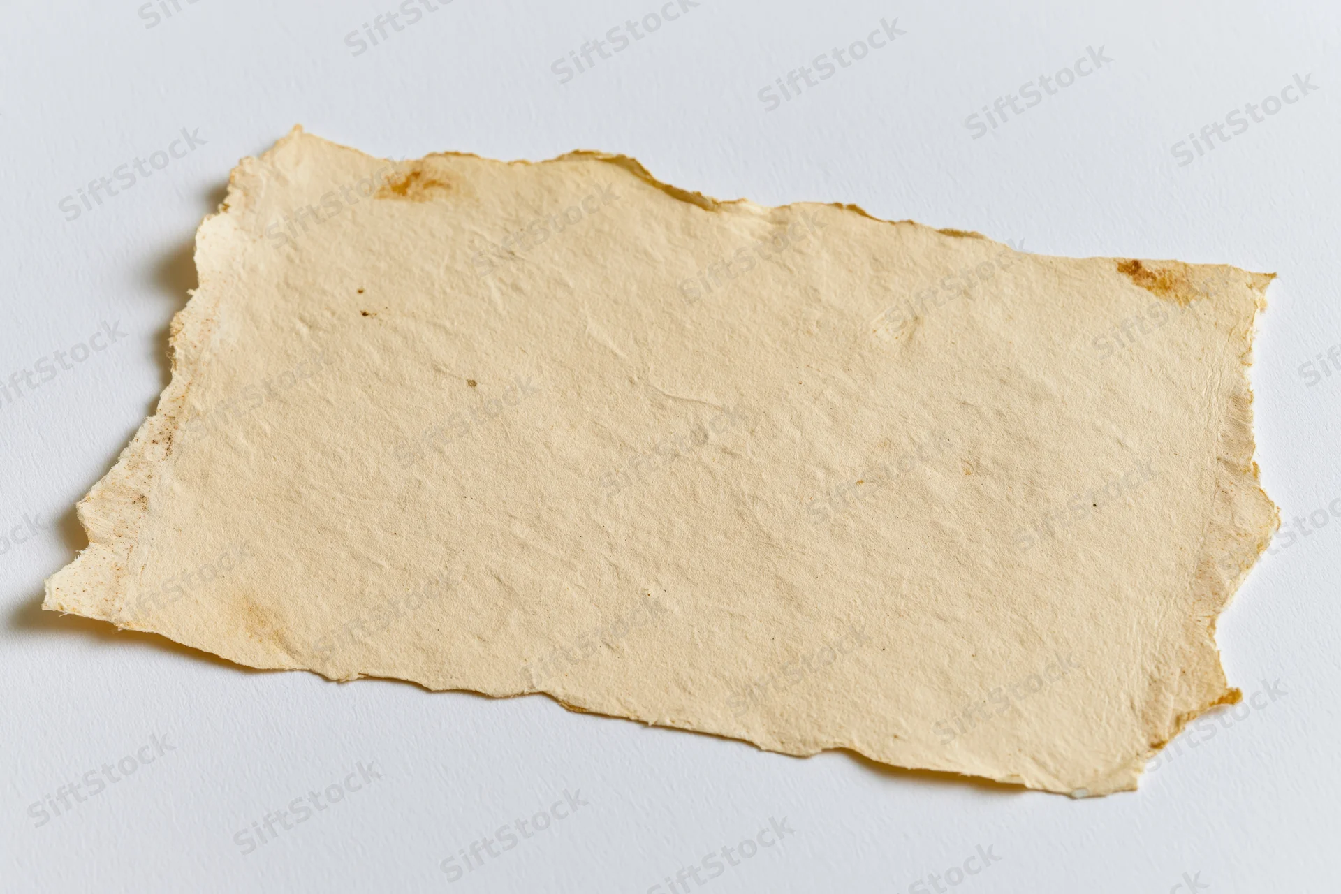 Torn aged paper lying flat on white surface
