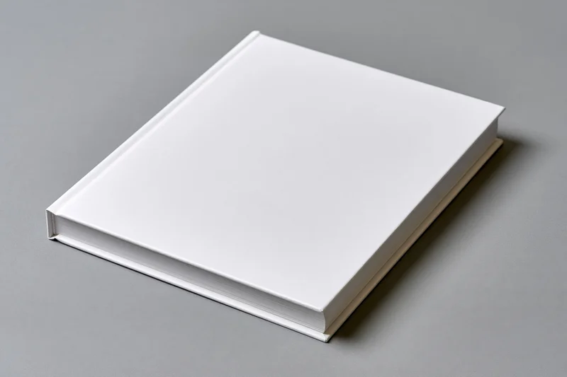 Blank white hardcover book lying flat on gray surface with copyspace