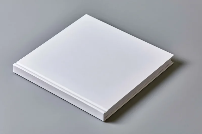 Blank white hardcover book lying flat on gray surface with copyspace