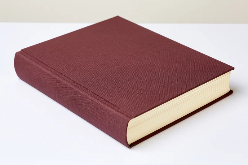 Hardcover book with maroon cloth cover resting on white surface