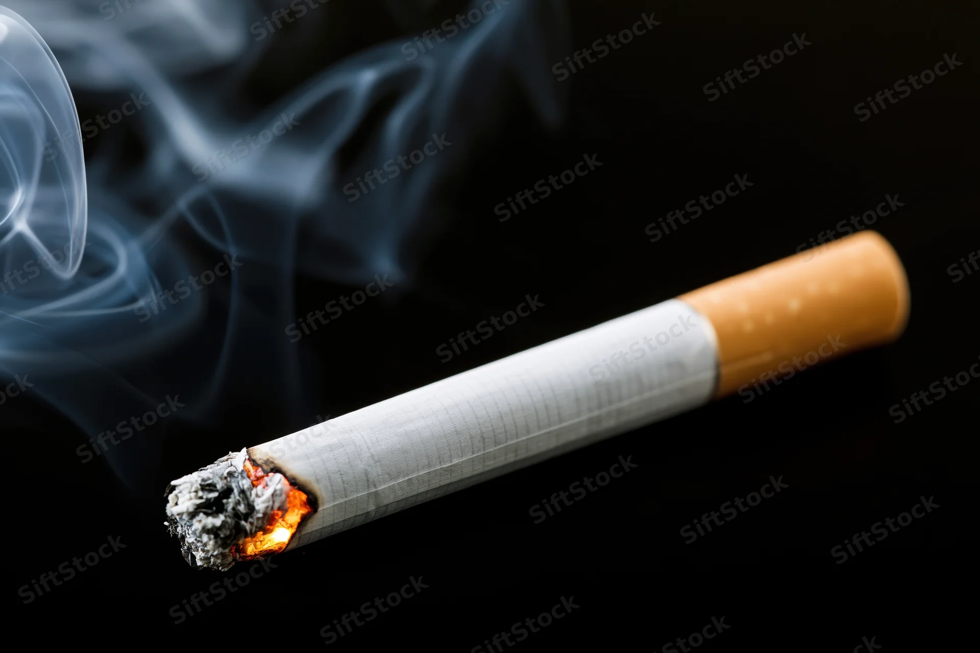 Lit cigarette with glowing ember and rising smoke against black background