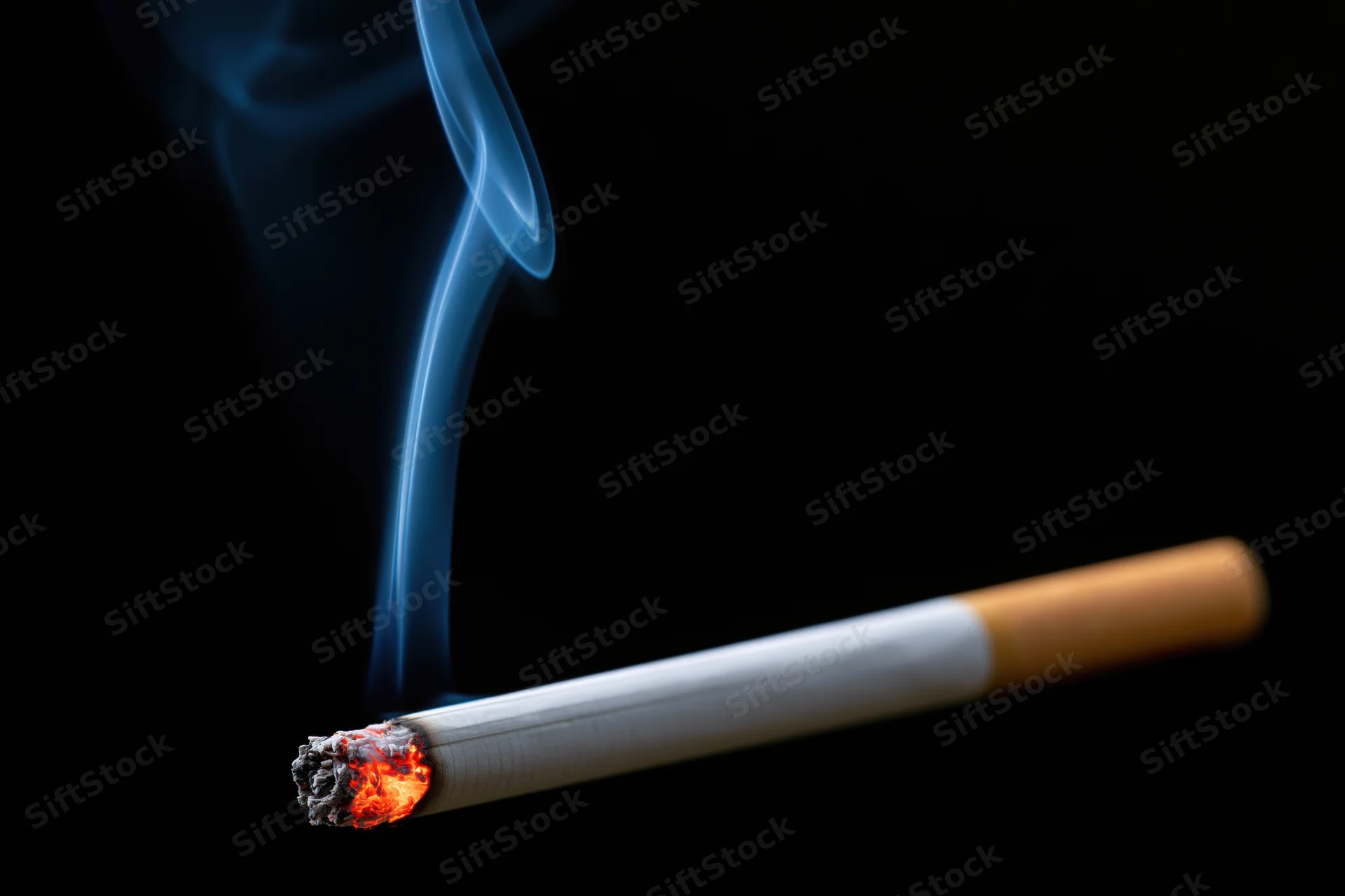 Lit cigarette with glowing ember and rising smoke against black background