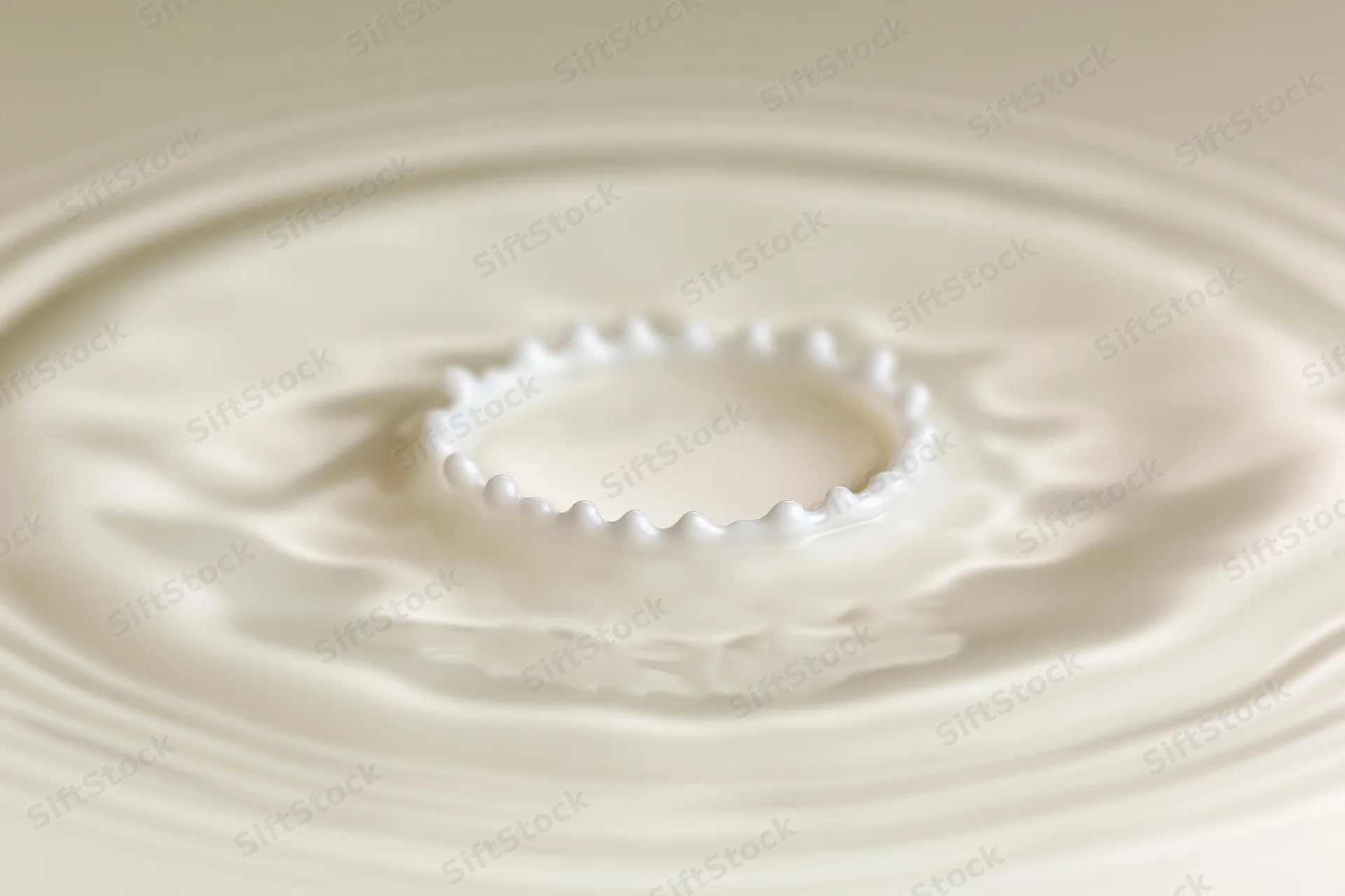 Milk drop creating crown splash on flat surface with ripples spreading outward