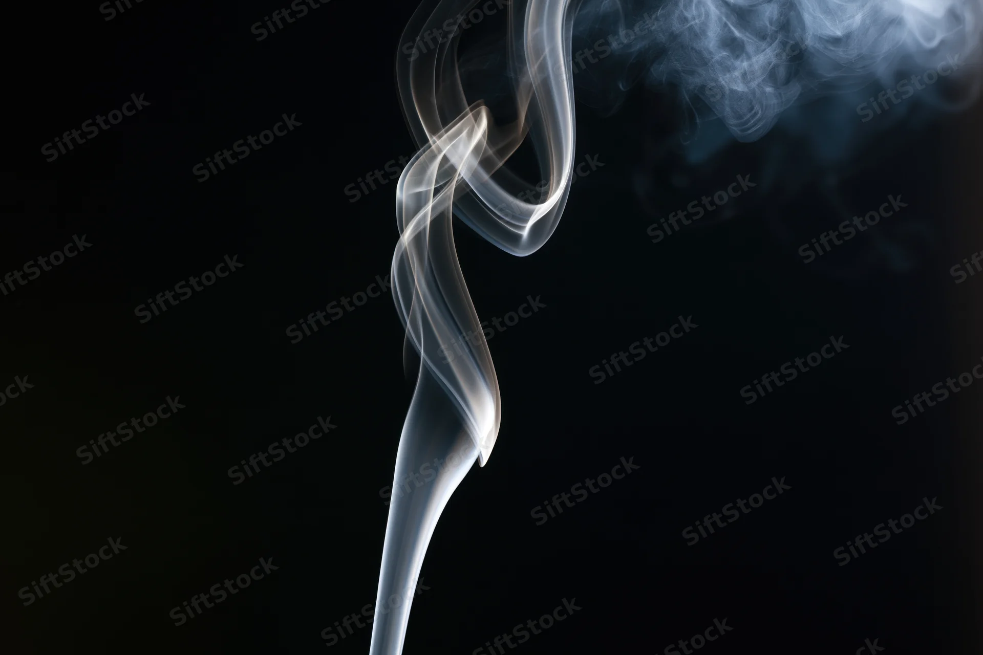 Thin wisp of white smoke rising and curling against black background