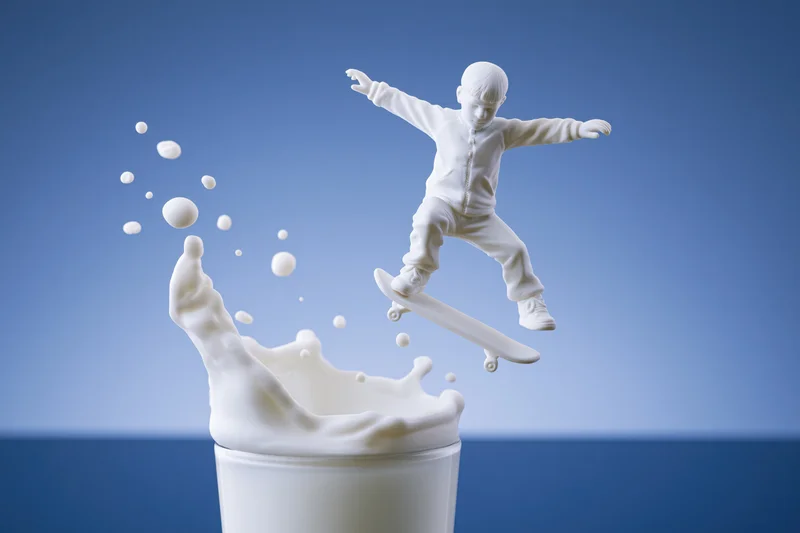 White milk sculpture of a child skateboarding mid-air above a splashing carton
