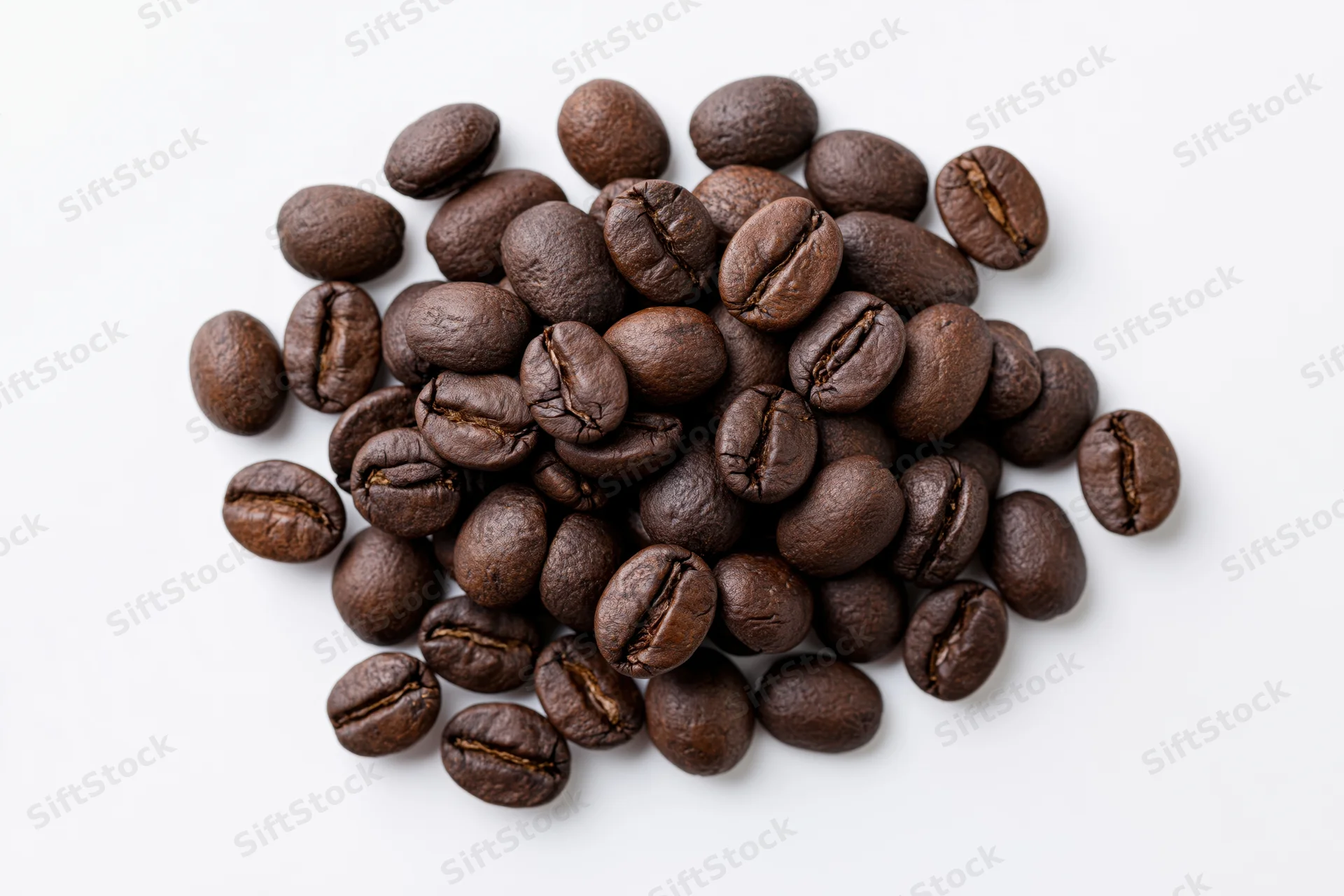 Dark roasted coffee beans scattered in a loose pile on white background
