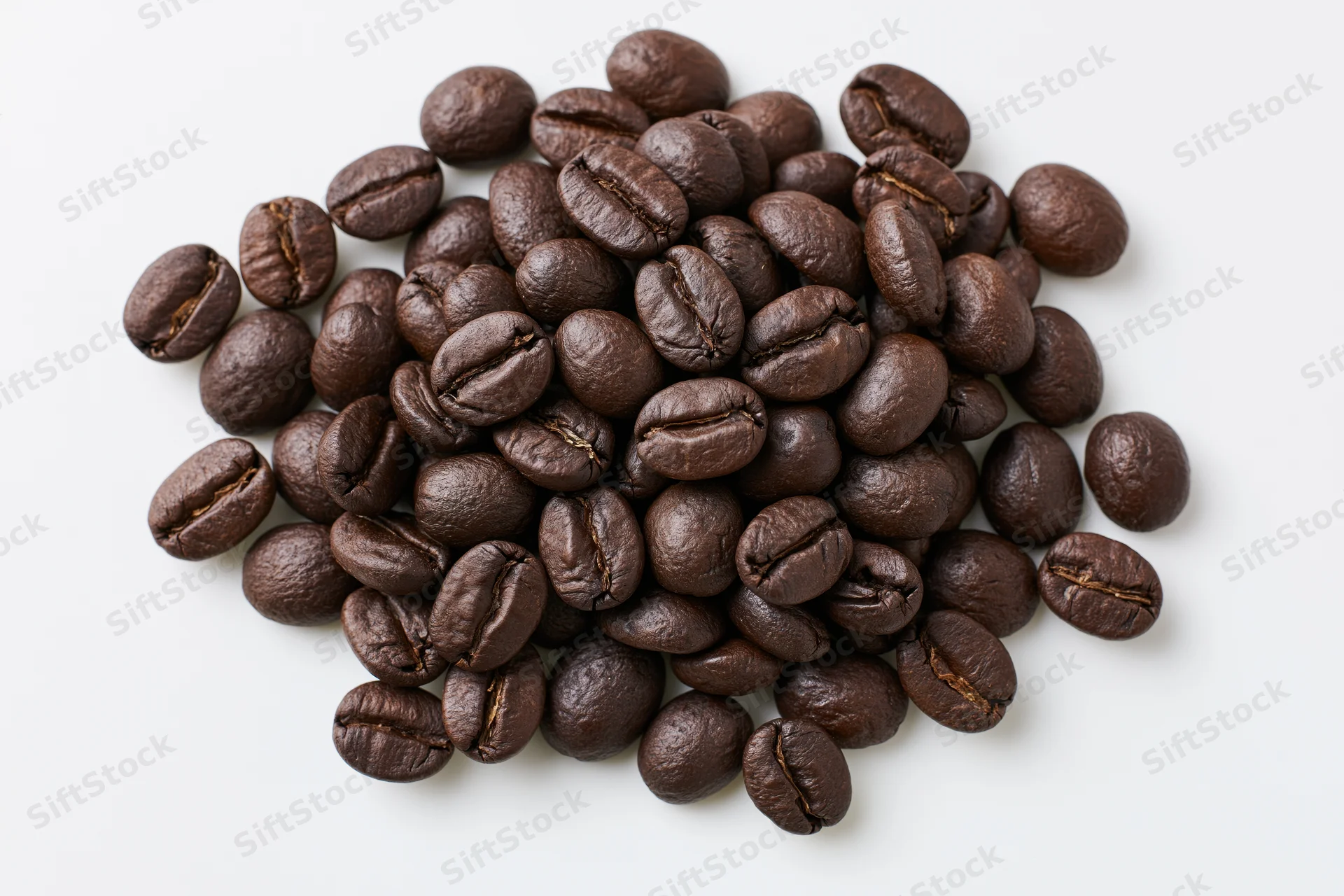 Dark roasted coffee beans scattered in a loose pile on white background