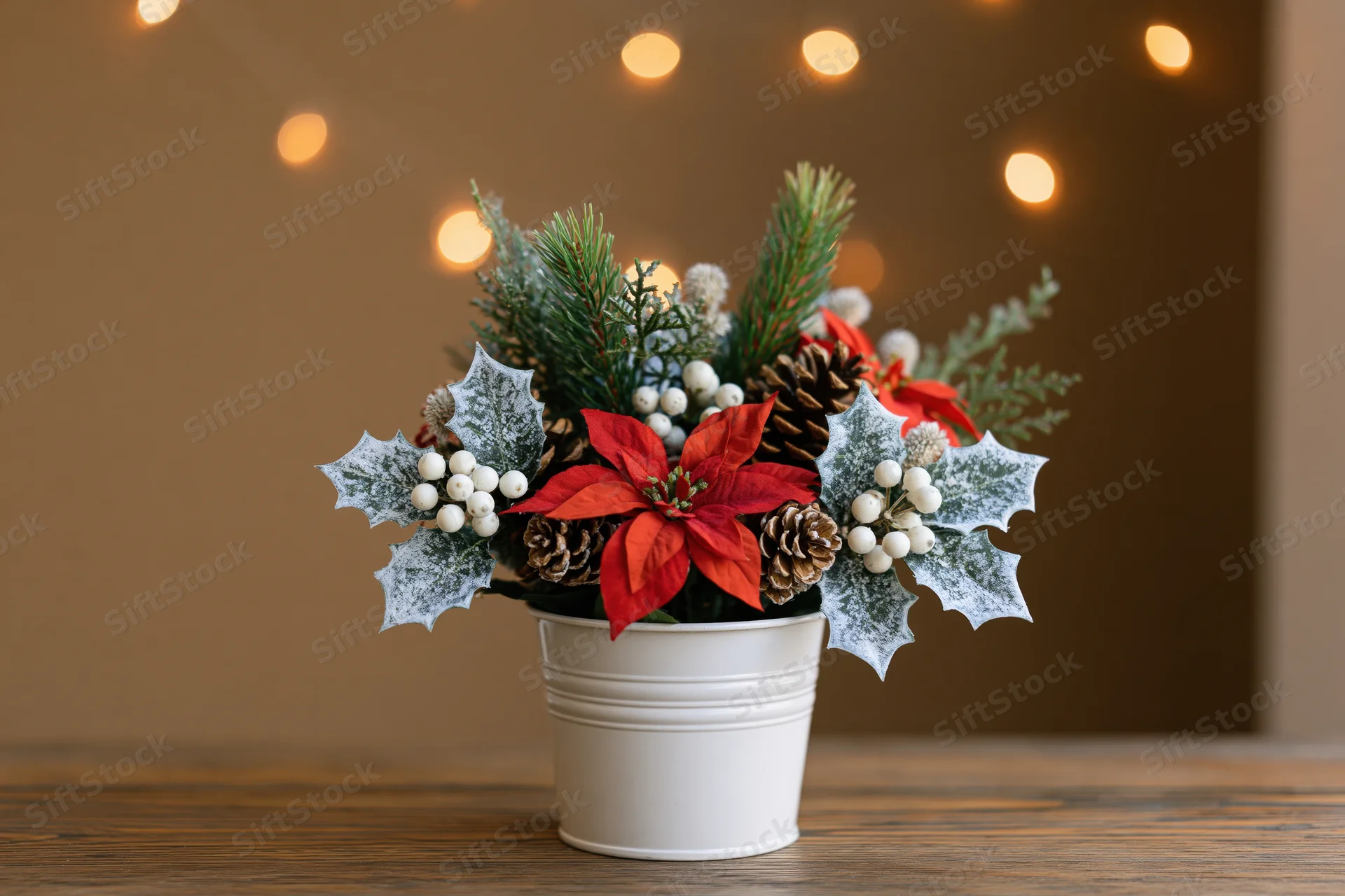 Christmas floral arrangement in a white metal bucket on a wooden table with warm bokeh lights in the background
