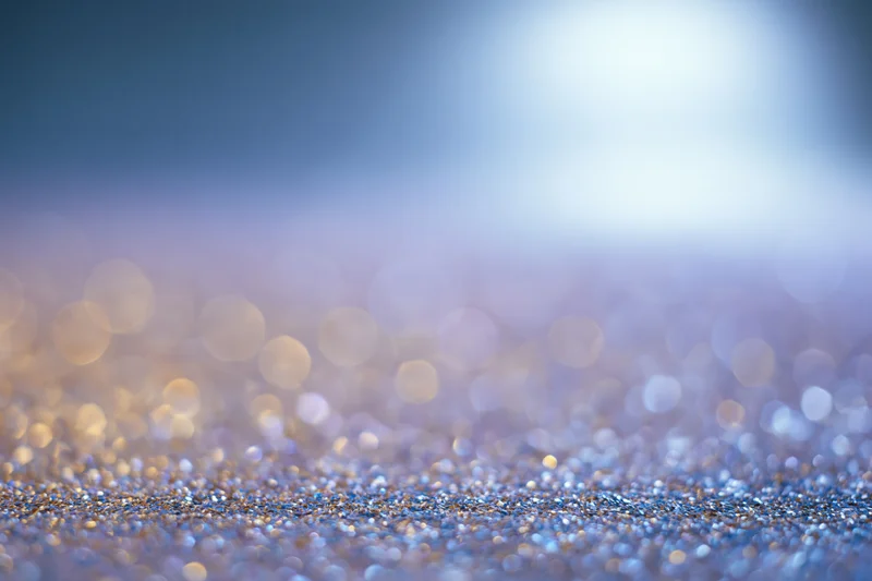 Abstract glitter surface with scattered light orbs and soft bokeh background