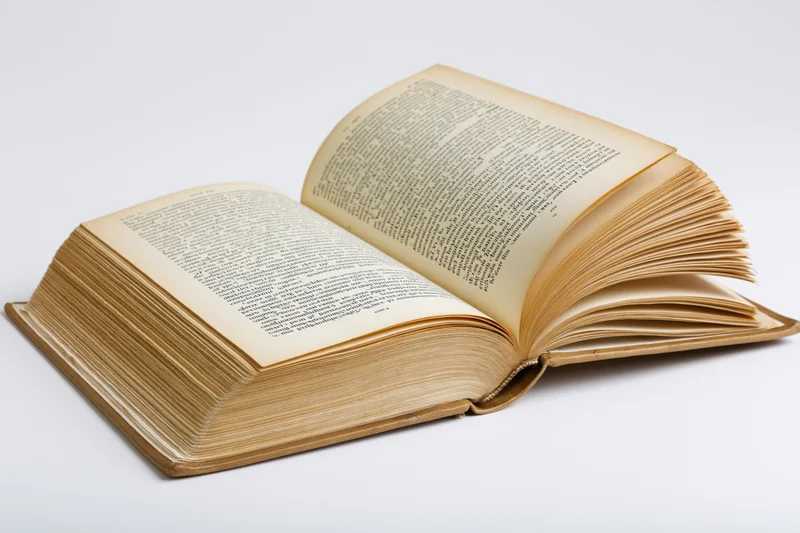 Open vintage hardcover book with fanned and arched pages on white background