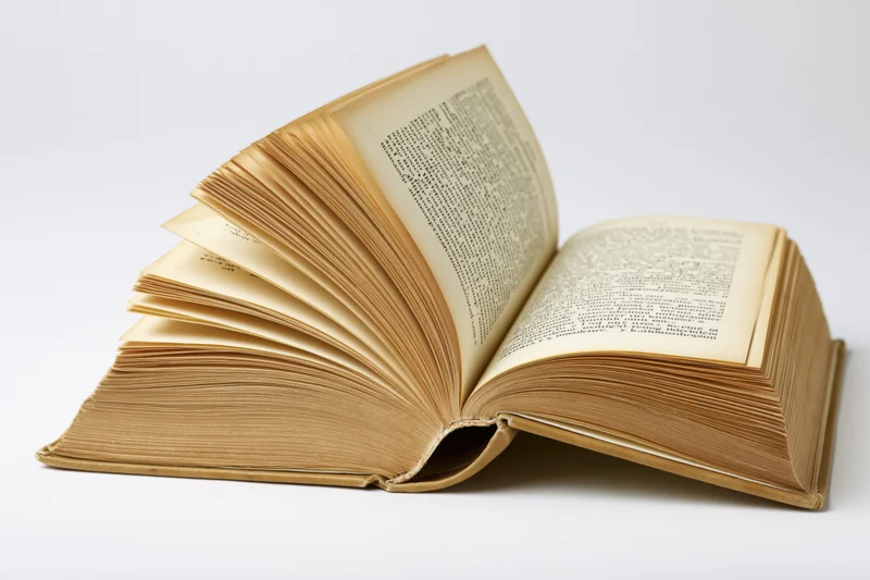 Open vintage hardcover book with fanned pages arched on white background