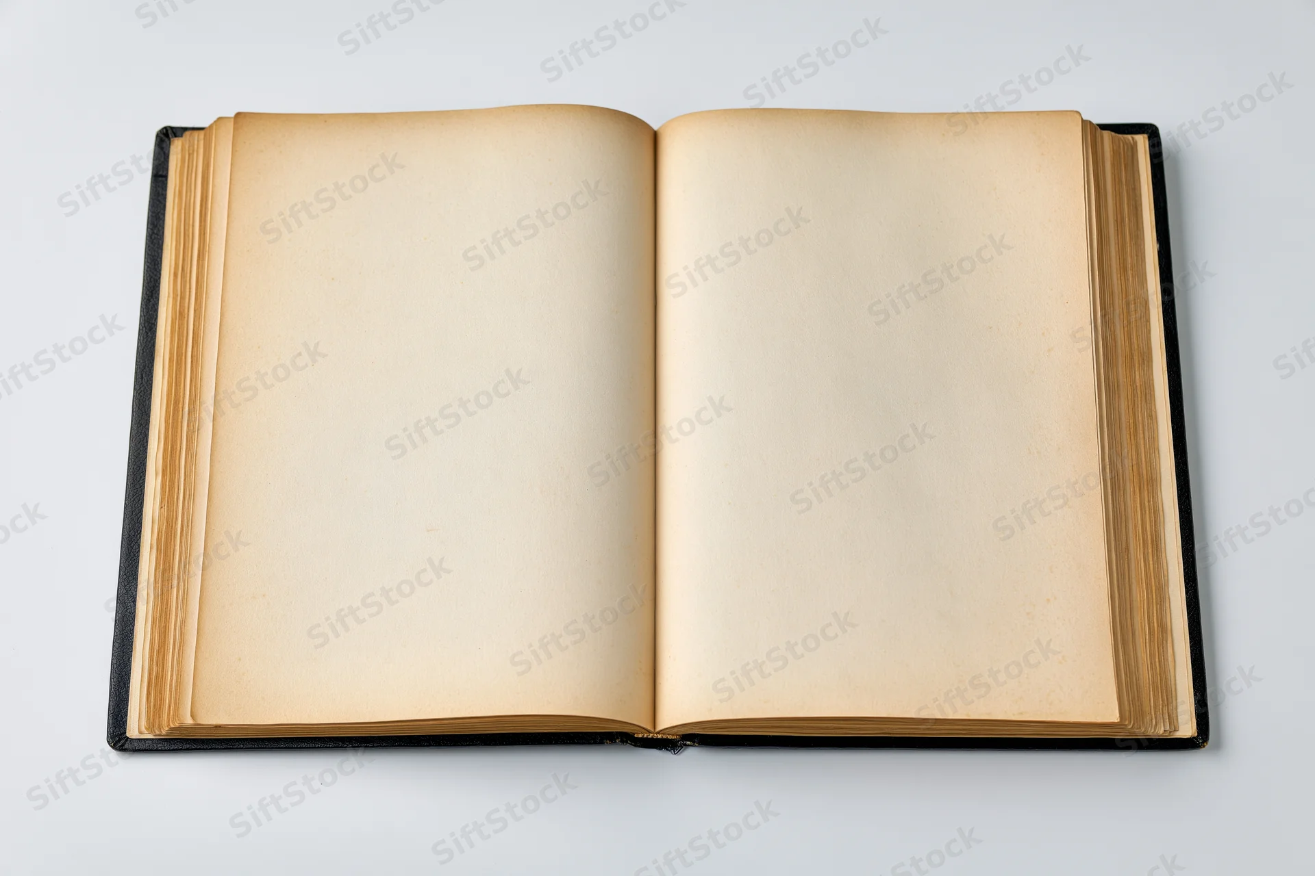 Open hardcover book with blank yellowed pages on white surface