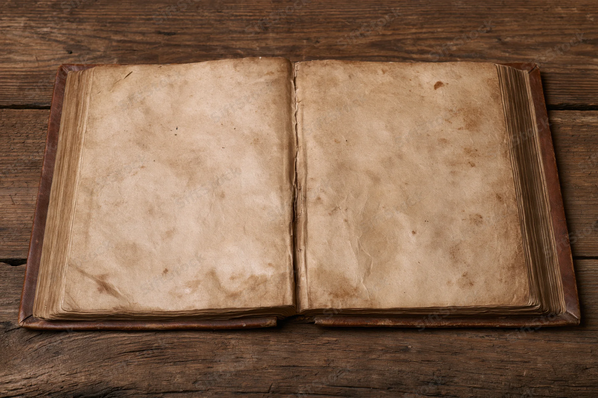 Open vintage book with blank aged pages lying flat on a rustic wooden table