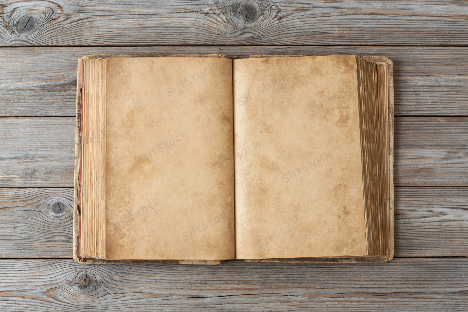 Open vintage hardcover book with blank yellowed pages on a weathered wooden table