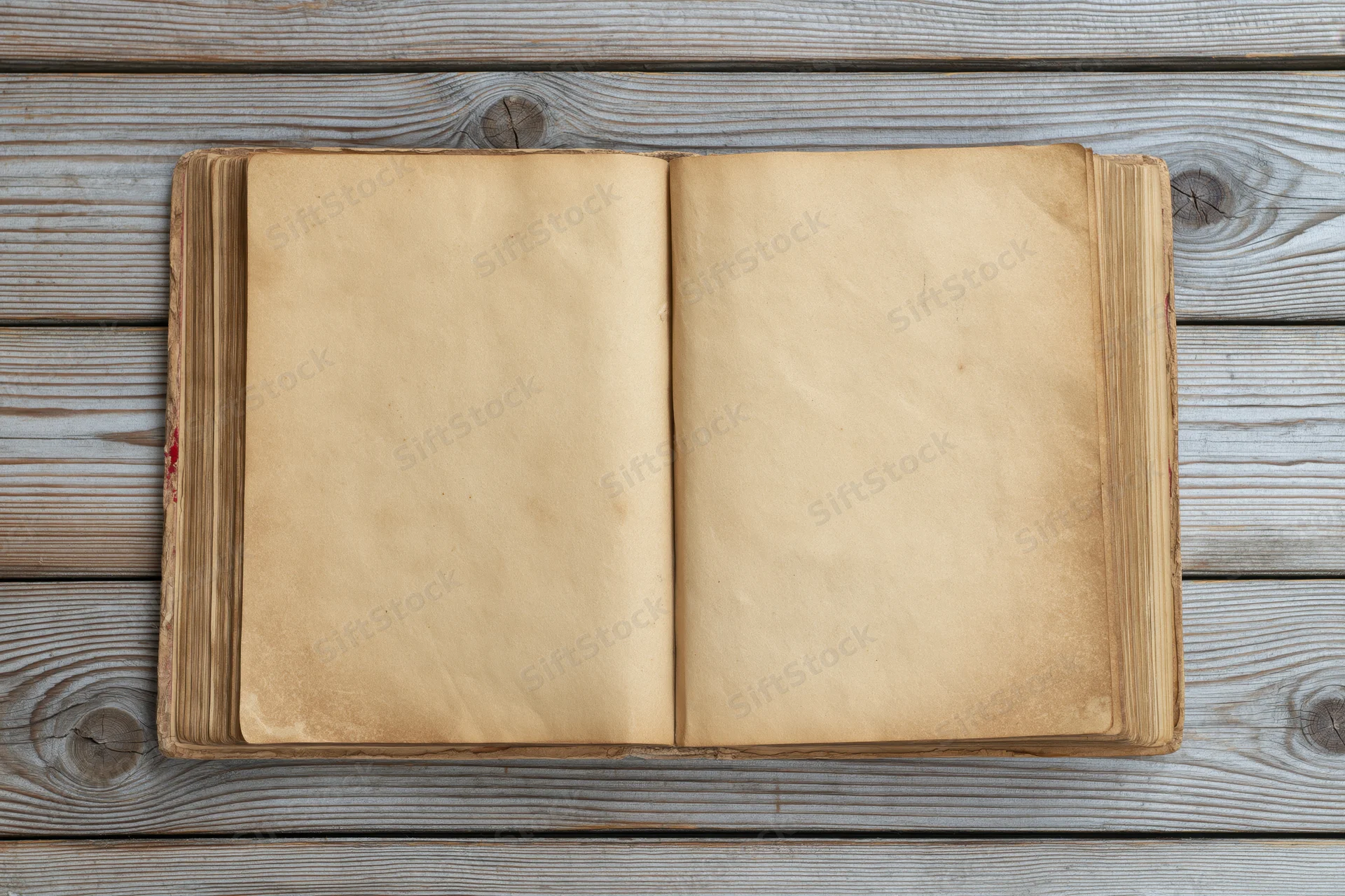 Open vintage hardcover book with blank yellowed pages on wooden surface