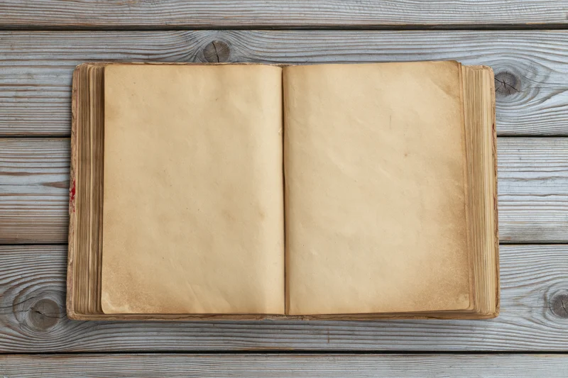 Open vintage hardcover book with blank yellowed pages on wooden surface