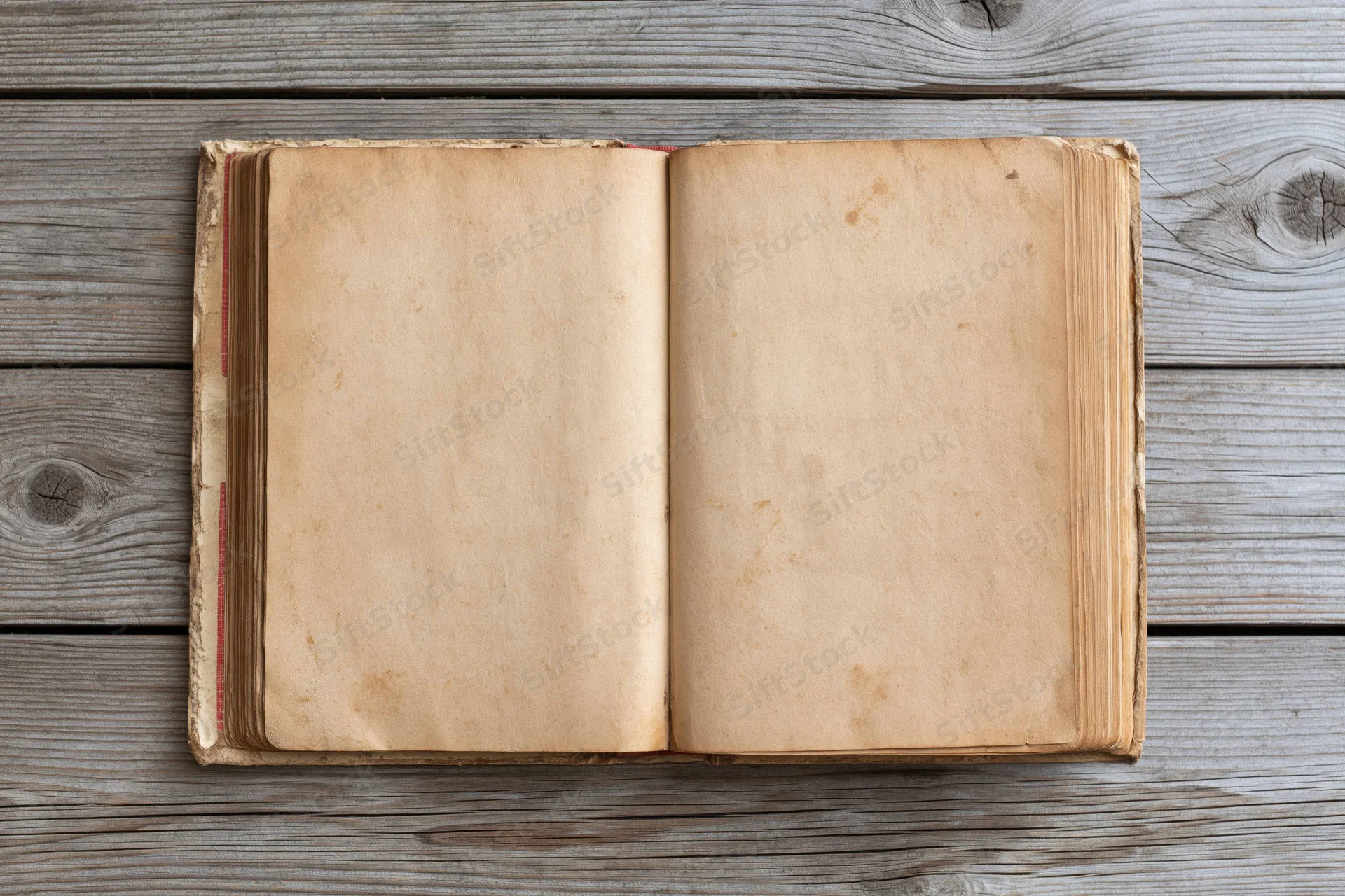Open vintage hardcover book with blank yellowed pages lying flat on weathered wooden surface