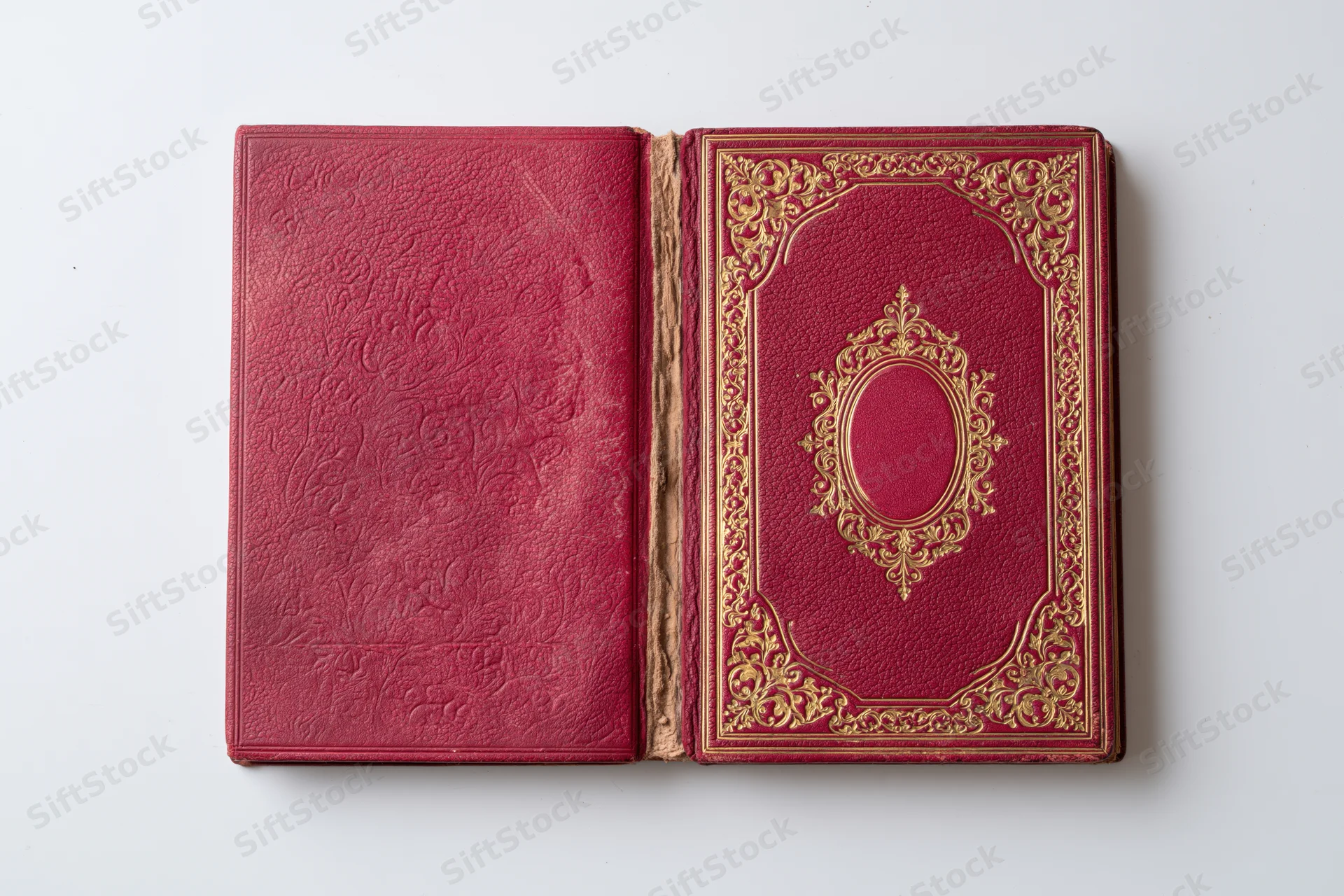 Open antique book with crimson leather covers and gold embossed decoration on white background