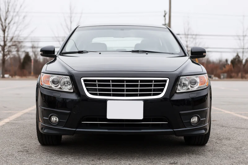Black compact sedan parked front view in empty asphalt lot