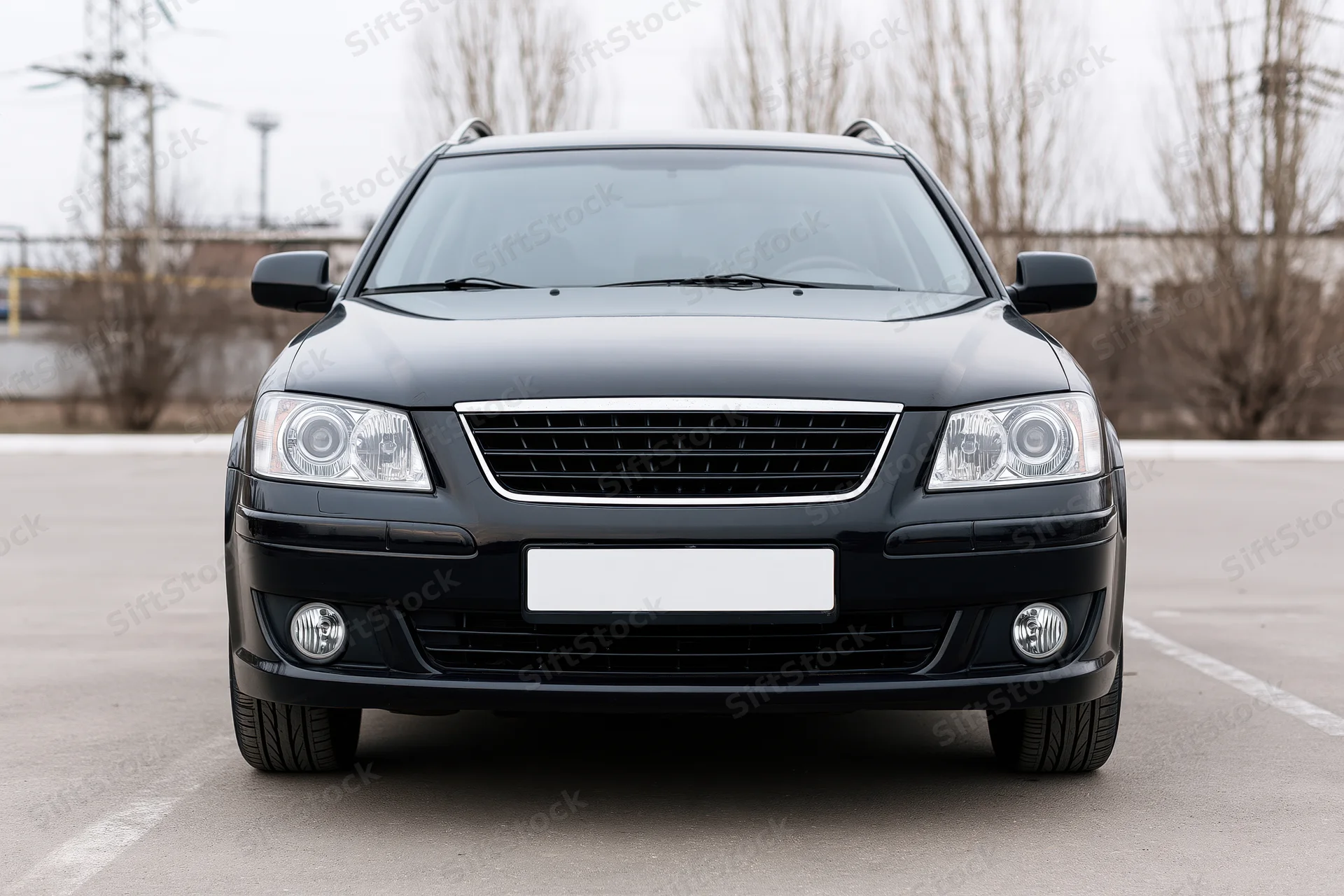 Black compact sedan parked front view on empty asphalt lot
