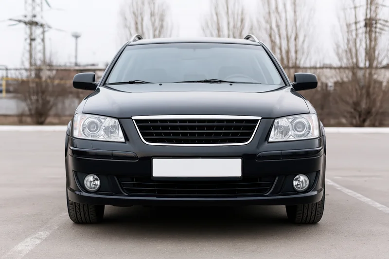 Black compact sedan parked front view on empty asphalt lot