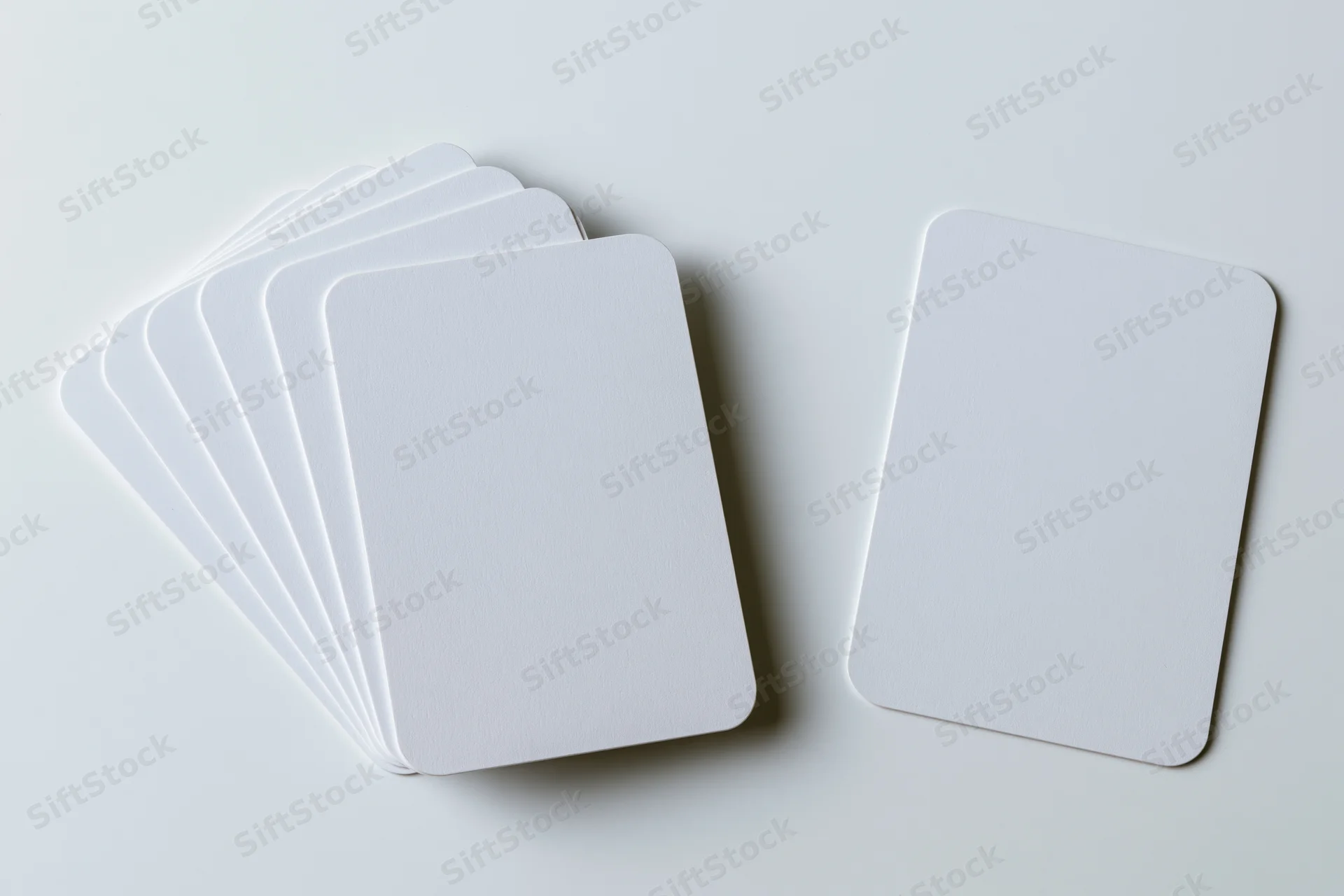 Blank white cards with rounded corners arranged in a fanned stack and single card on a clean white surface