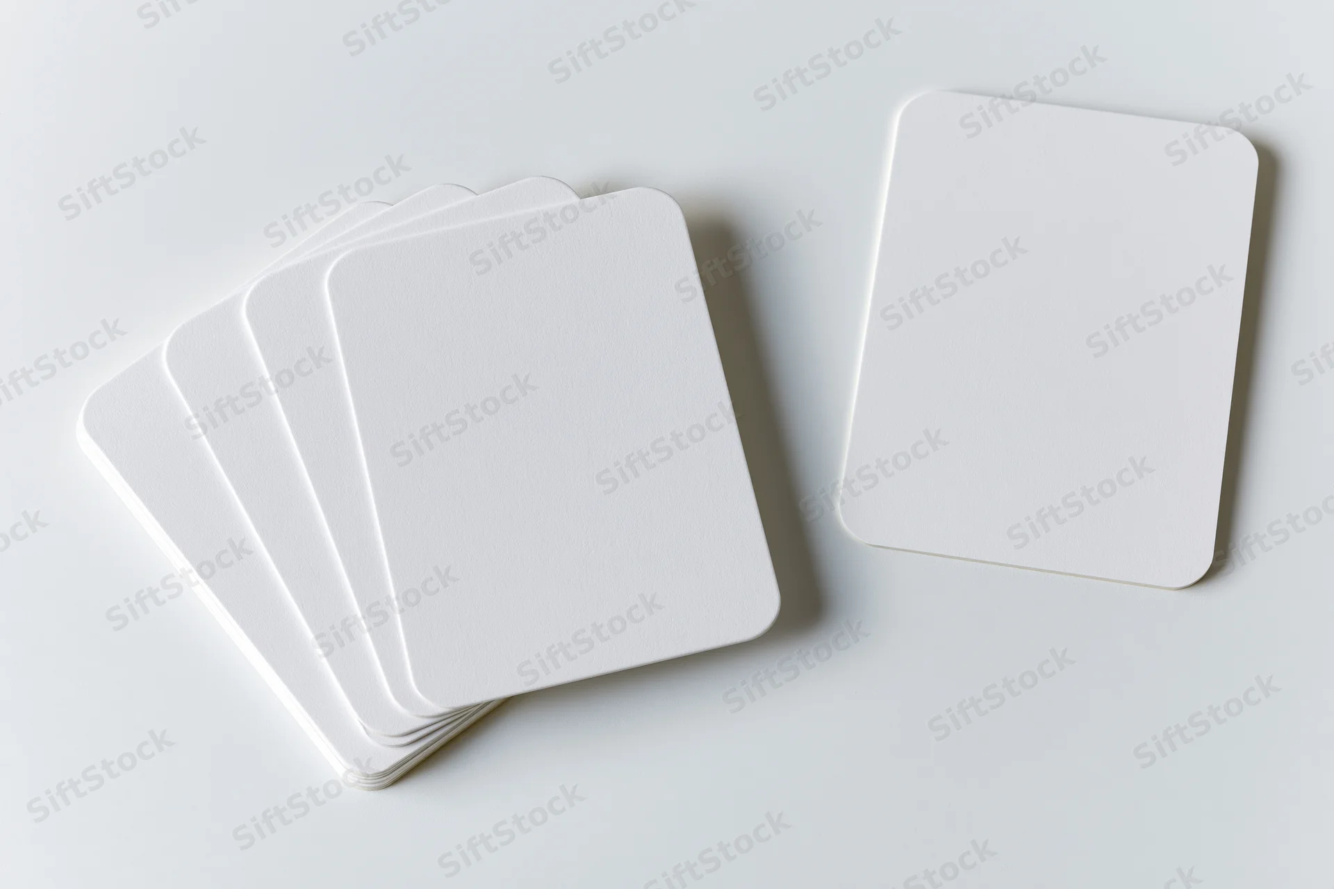 Blank white cards with rounded corners arranged in a stack and one separate on a clean white surface