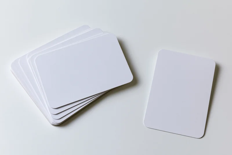 Blank white cards with rounded corners arranged in a stack and one separate on a clean white surface