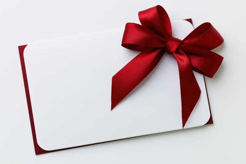 Blank white gift card with red satin ribbon bow on white background