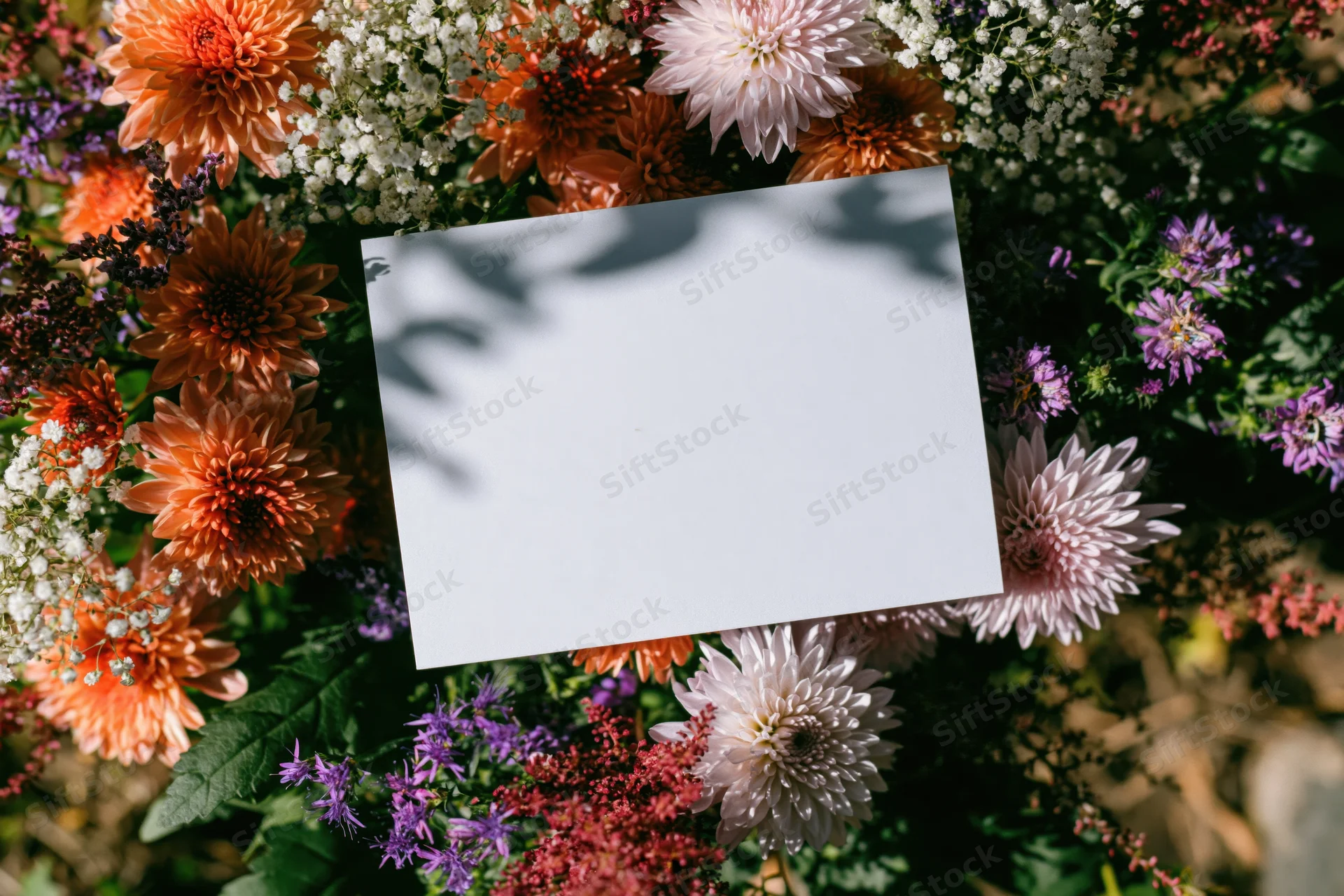 Blank white card resting on a colorful floral arrangement outdoors