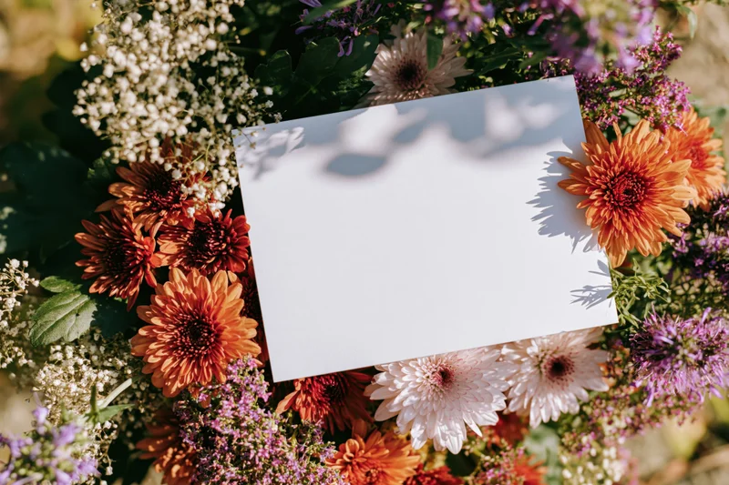 Blank white card resting on a colorful floral arrangement outdoors