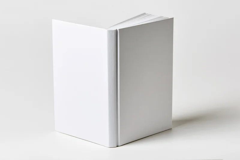Blank white hardcover book standing upright on a plain white surface with visible spine and pages