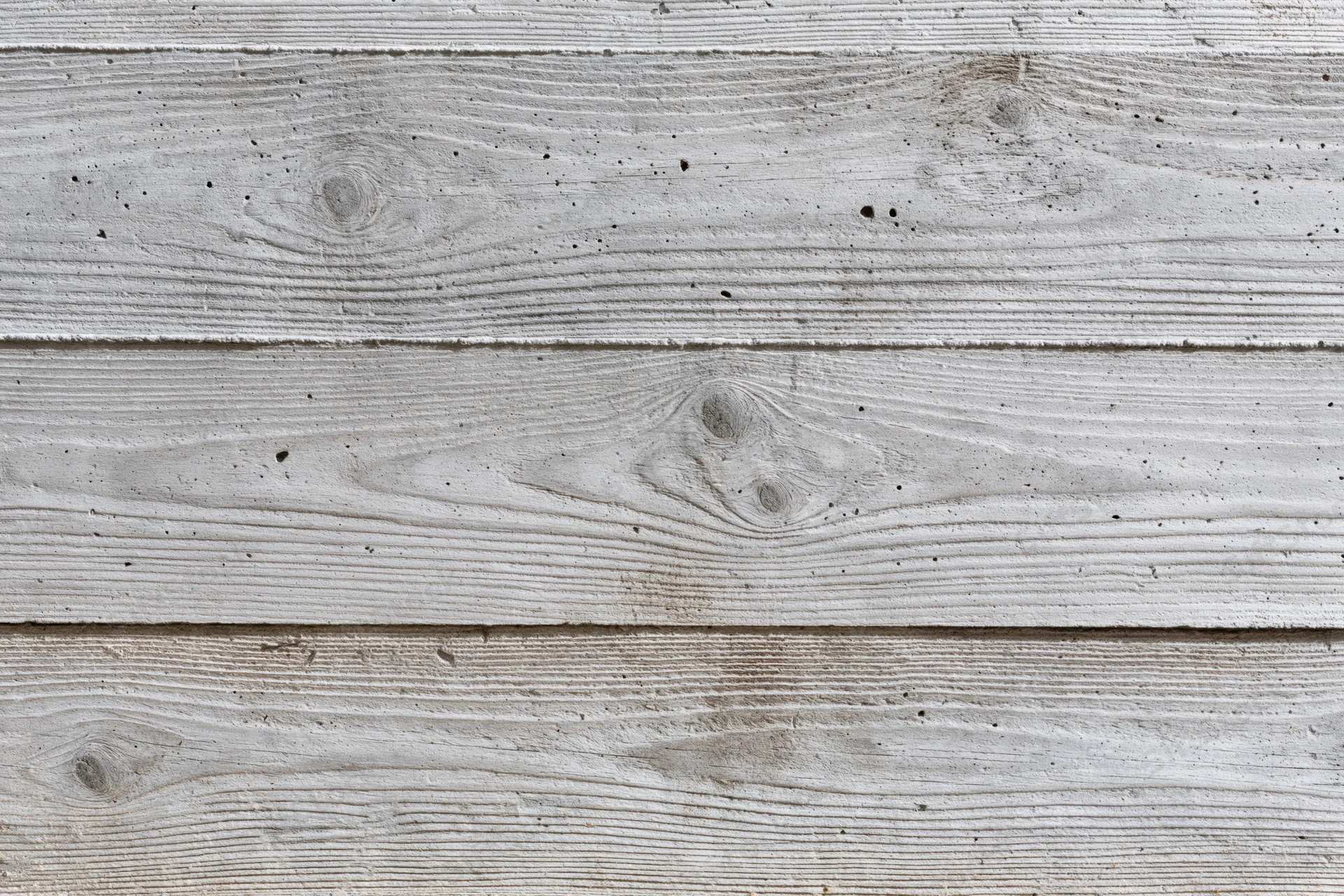 Board-formed concrete wall surface filling the frame with horizontal panels and visible texture
