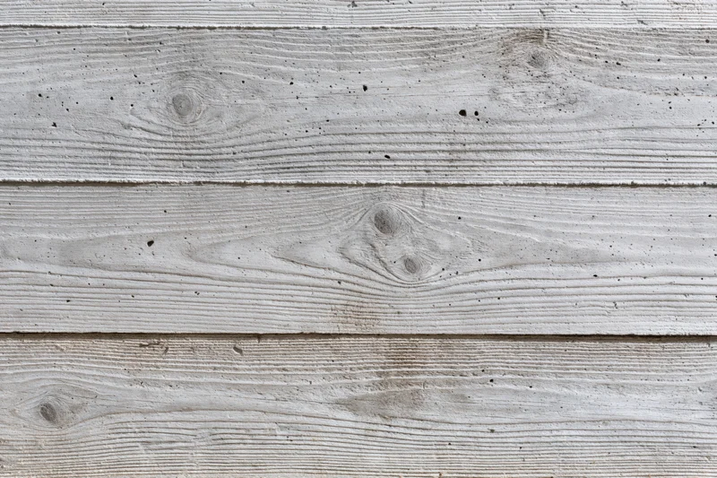 Board-formed concrete wall surface filling the frame with horizontal panels and visible texture