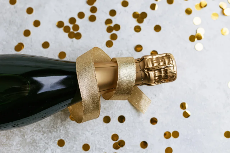 Champagne bottle lying on its side with a curled gold ribbon