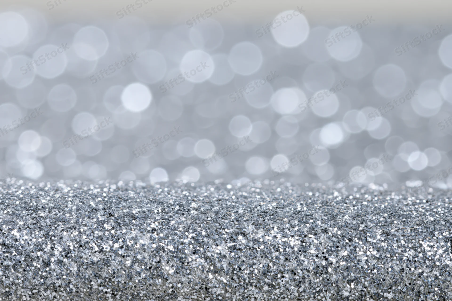 Close-up of silver glitter fabric surface with blurred bokeh background