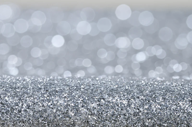 Close-up of silver glitter fabric surface with blurred bokeh background