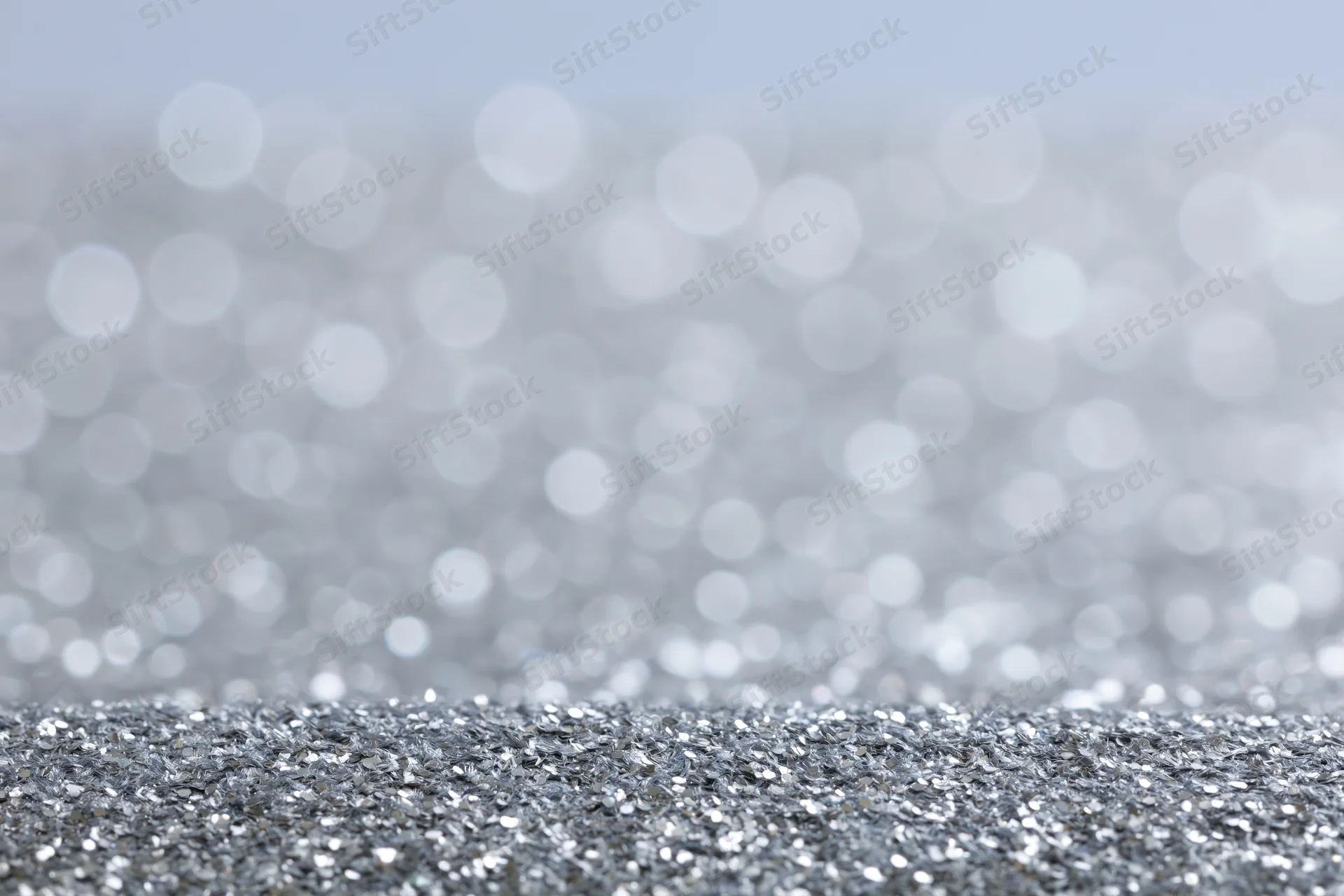 Close-up of silver glitter fabric surface with bokeh background