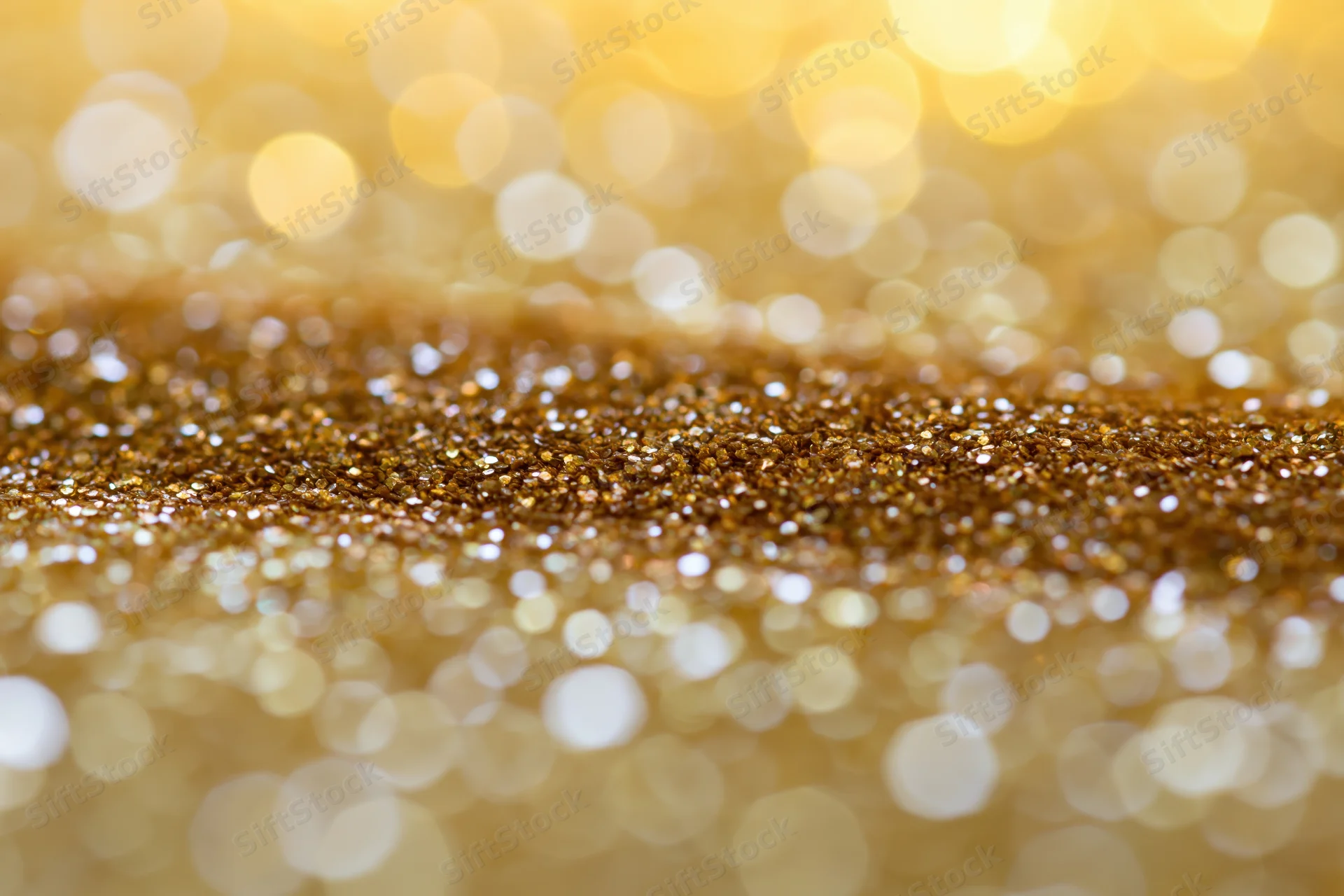 Close-up of scattered gold glitter particles with bokeh lights in the background