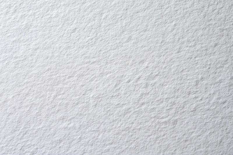 Close-up of a blank white textured paper sheet lying flat as a background